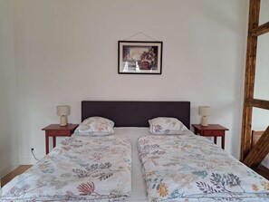 A double bed with floral bedding, two bedside tables with lamps, a wooden headboard, and a framed picture on the wall.
