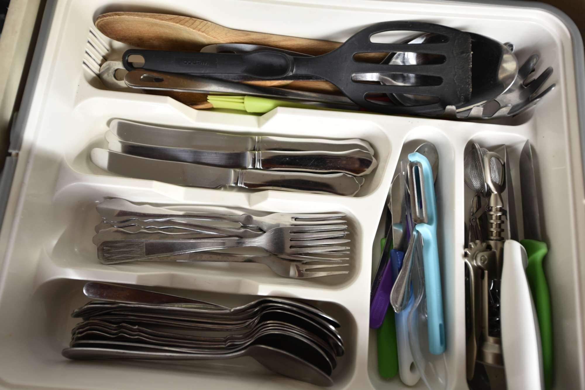 Un cajón con varios utensilios de cocina, incluyendo una espátula, cuchillo, tenedor y cuchara.