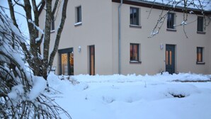 A building with multiple windows and doors, surrounded by snow. - Eifelgold - Comfortable, spacious 5-star apartment in a quiet location  (Habscheid)