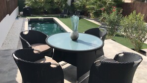 A patio with a pool, outdoor furniture, and greenery. - Modern bungalow with heated pool, 50m from the sea - whirlpool - (Cala Pi)