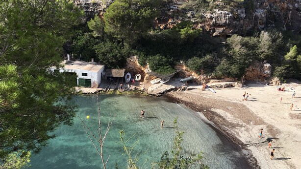 A coastal area with a clear beach, rocky cliffs, and a small building with a roof. - Modern bungalow with heated pool, 50m from the sea - whirlpool - (Cala Pi)