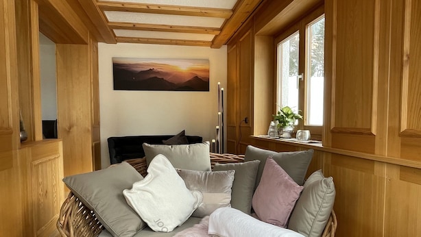 Una habitación acogedora con detalles de madera, una cama con almohadas, una ventana con vistas y un cuadro en la pared.