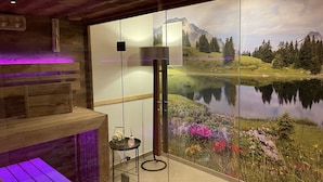 Un cuarto de spa con un banco de madera, una mesita con una vela y un mural en la pared de un lago y montañas.