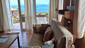 Un sofá de madera con cojines estampados en una habitación con vistas al mar.