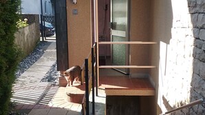 Ein kleiner, abgeschlossener Außenbereich mit Holzterrasse, Metallgeländer und Steinmauer.