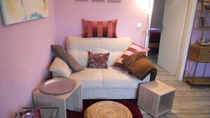 Ein Wohnzimmer mit einer Couch, Kissen, einem kleinen Tisch und einer Lampe.