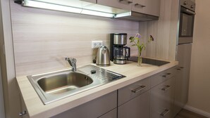 A modern kitchen with a stainless steel sink, a coffee maker, and a vase with flowers. - Quiet living in the heart of Görlitz in elegant style (Görlitz)