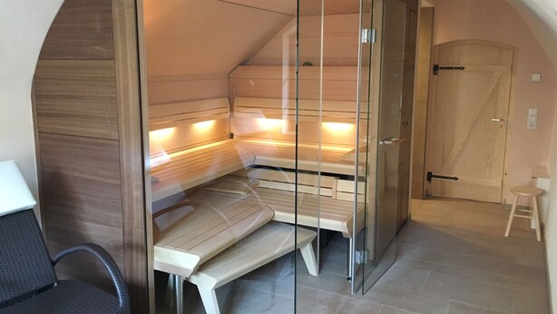 A sauna room with a bench, glass walls, and a wooden door. - Quiet living in the heart of Görlitz in elegant style (Görlitz)