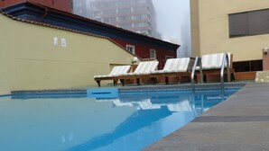 A swimming pool with lounge chairs and a building in the background. - MALECÓN BALTA: best location, friendly service, clean & comfortable, safe (Miraflores)