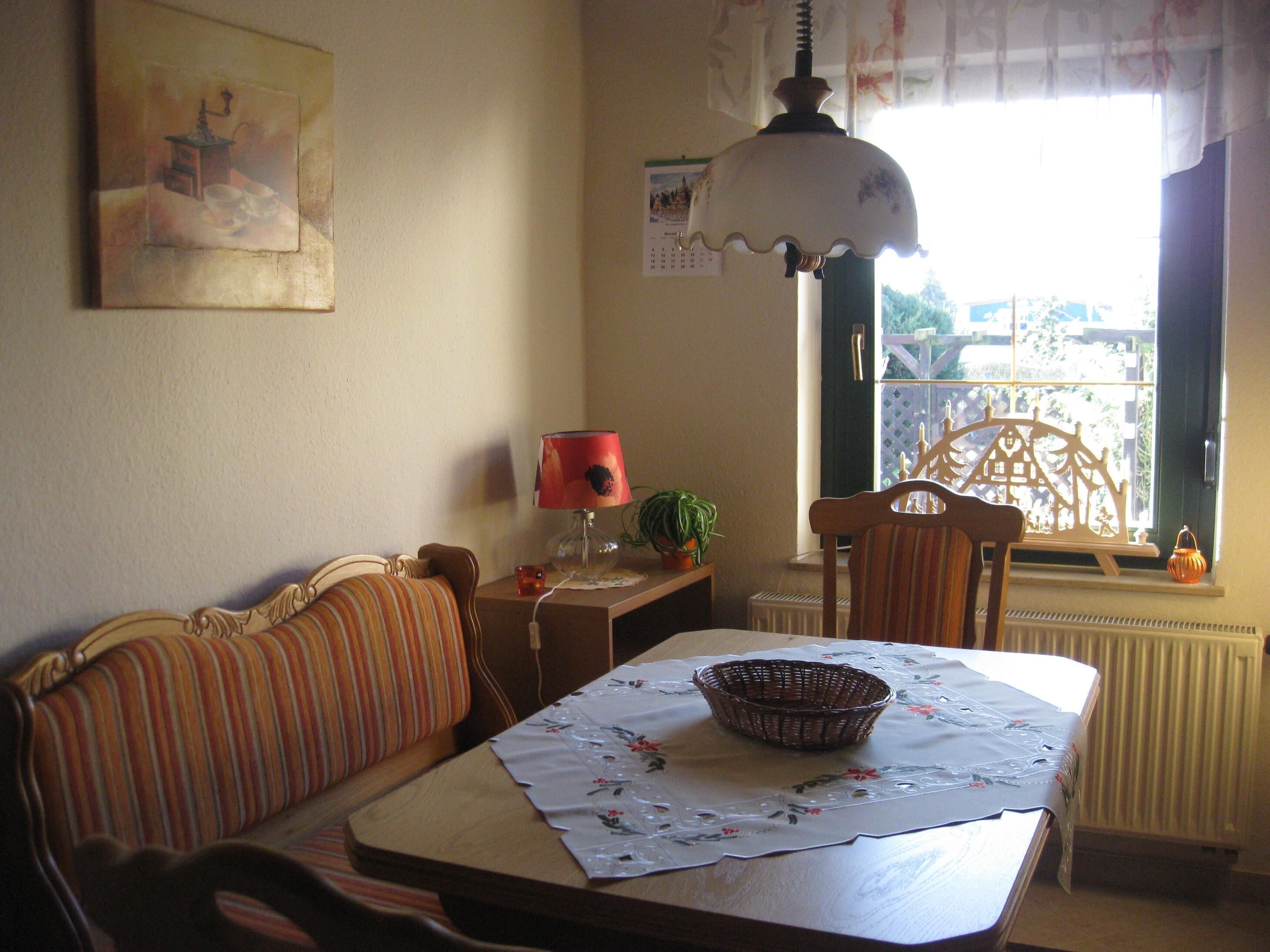 Un comedor con una mesa dispuesta para dos, un sofá a rayas, una lámpara y un ventanal con vistas.