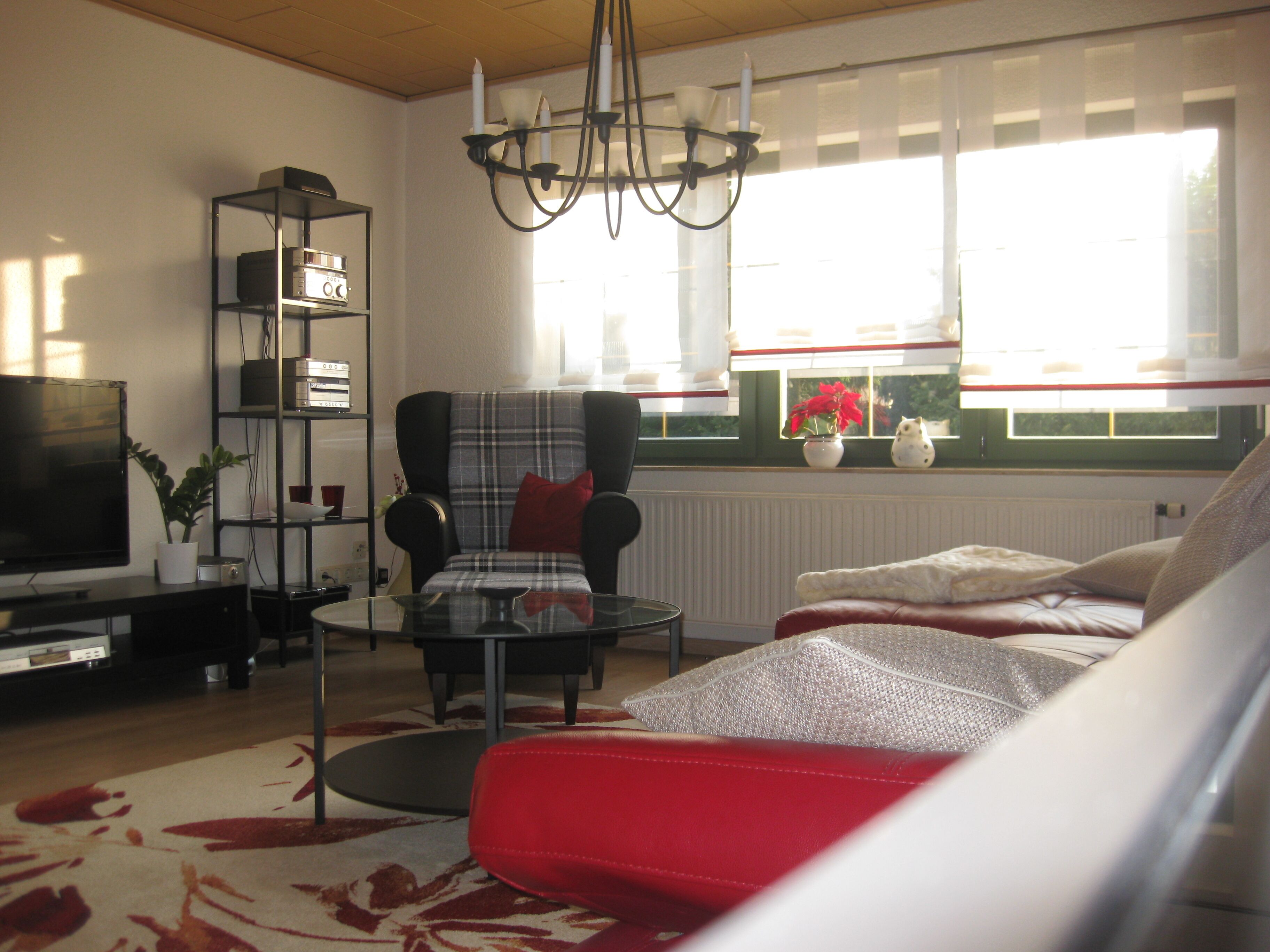 Una sala de estar con televisión, una silla, un sofá, una mesa baja y una estantería.