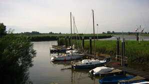 Un río tranquilo con barcos amarrados a un muelle de madera.
