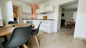 A modern kitchen with white cabinets, a wooden dining table, and black chairs. - Welcome to the Oderbruch (Wriezen)