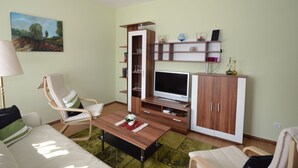 Una sala de estar con sofá, mesa de centro, mueble para televisión y estantería.