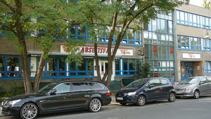 Un edificio con varias fachadas, incluyendo una con un cartel que dice 'BERLINER PIZZA'.