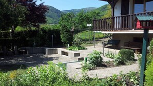 A garden with a wooden deck, a bench, and a view of mountains.