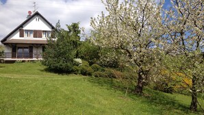 A house with a sloped roof, a balcony, and a well-maintained lawn.