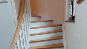 A wooden staircase with white walls and a white door.