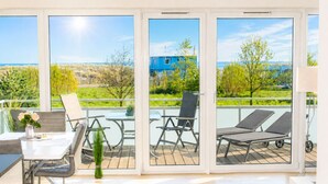 Un balcon avec une table, des chaises et un fauteuil.