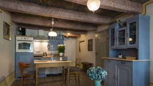 Une cuisine avec une table en bois, des chaises, un vase et des placards.
