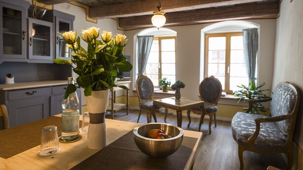 Un coin repas avec une table en bois, des chaises, un vase de fleurs et un saladier.