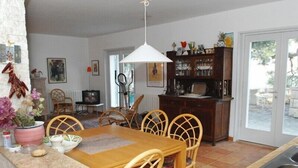 A dining area with a wooden table and chairs, a kitchen counter, and a dining table with a white pendant light. - Villa located directly at the sea (Klek)