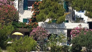 A coastal building with a stone facade, a stone staircase leading to a patio, and a small stone oven. - Villa located directly at the sea (Klek)
