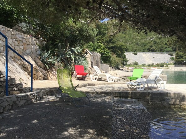 A poolside area with stone walls, a stone staircase, and several lounge chairs.