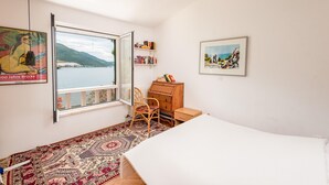 A room with a large window, a bed, a chair, a wooden dresser, and a bookshelf. - Villa located directly at the sea (Klek)