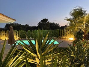 Une piscine entourée de verdure et un espace abrité agrémenté d’une pergola.