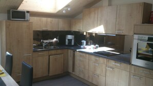 A compact kitchen with wooden cabinets, a microwave, a coffee maker, and a stove.