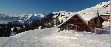 A snow-covered mountain with wooden cabins and ski tracks.