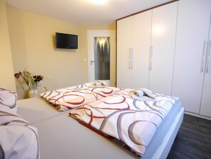 Una camera da letto con un letto, una televisione a muro e un armadio.