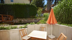 A patio with a table and chairs, a small pond, and a wooden deck. - House Family Trube FeWo2 (Heringsdorf)