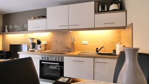 A modern kitchen with white cabinets, a built-in oven, a coffee maker, and a sink. - House Family Trube FeWo2 (Heringsdorf)