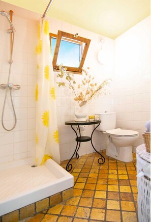 Bathroom features a bathtub, toilet, and a small table with a vase.