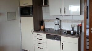 A compact kitchen with a microwave, coffee maker, and dishwasher. - Experience the Baltic Sea up close and intense. (Haffkrug)