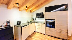 Une cuisine avec des poutres en bois, un four à micro-ondes, une cuisinière et un évier.