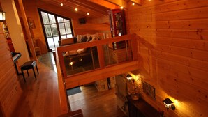 A cozy cabin interior with a loft bedroom, a dining area, and a kitchen.