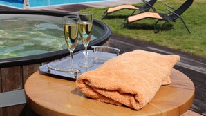 A hot tub with two glasses of champagne and a towel on a wooden table.