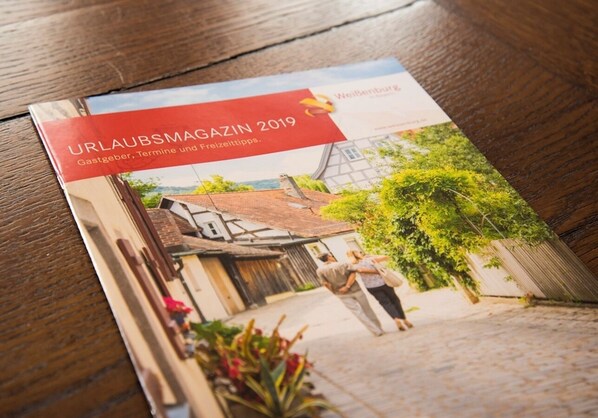 Une brochure intitulée « URLAUBSMAGAZIN 2019 » illustrée avec une scène de rue.