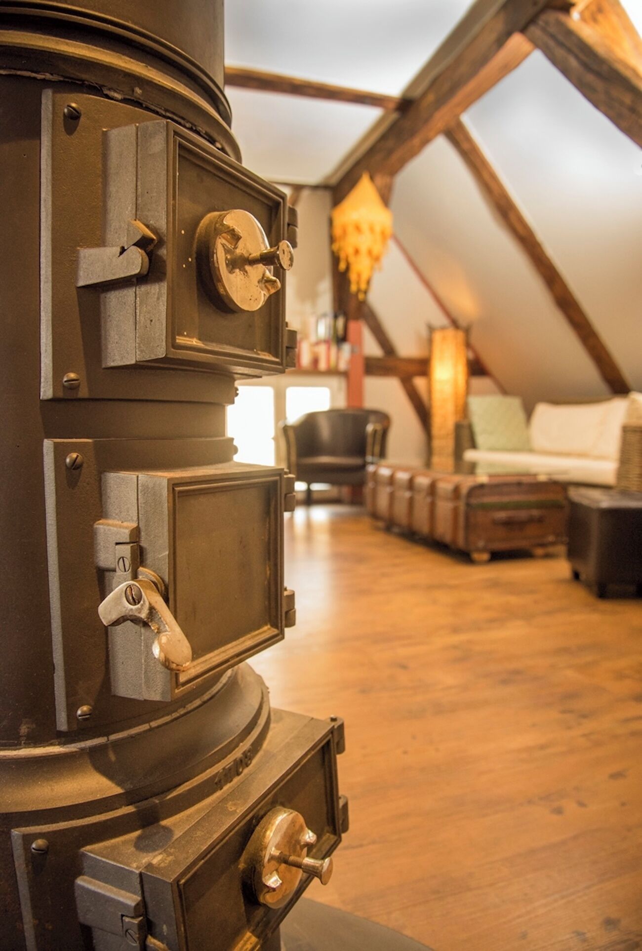 A wood-burning stove in a room with wooden beams and a sofa.