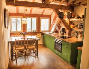 Eine Küche mit einem Holztisch, Stühlen und einem grünen Schrank.