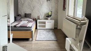 Ein modernes Schlafzimmer mit Bett, Nachttisch, Heizkörper und Fenster.