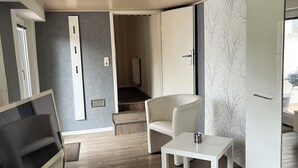 Ein modernes Zimmer mit Flachbildfernseher, einem weißen Tisch, einem Stuhl und einem Kleiderschrank.