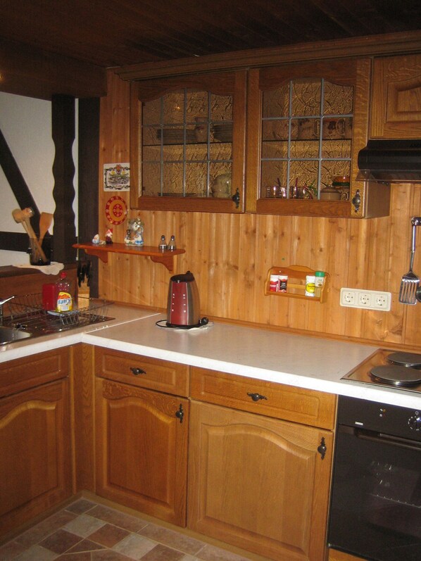 Une cuisine avec des meubles de rangement en bois, une cuisinière, une machine à café et une fenêtre ornée de vitraux.