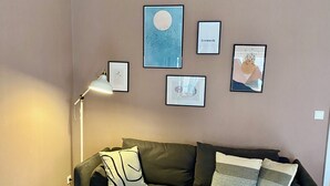 Una sala moderna con un sofá verde oscuro, una mesa de centro redonda de madera y una lámpara de pie.