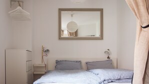 Un dormitorio con cama, lámparas de noche, un espejo y un armario.