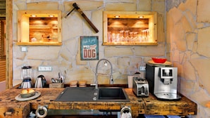 A rustic kitchen with a stone wall, wooden shelves, a coffee maker, a toaster, and a blender. - Apartment "Chiara" (Oybin)