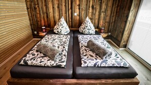 A room with two dark-colored sofas with patterned cushions, a wooden slatted wall, and a window with blinds. - Apartment "Chiara" (Oybin)